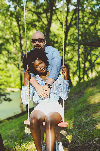 istock Affectionate Husband Embracing Wife From Behind While She's Sitting on Swing 2220405547