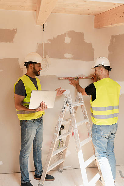 istock Two male Construction workers in safety vests leveling wall while working on a house renovation 2220406762
