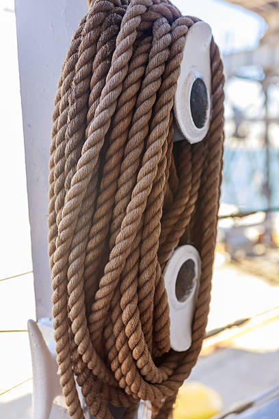 istock Thick brown nautical rope neatly coiled on large pulley hook aboard sailing ship. 2220407161