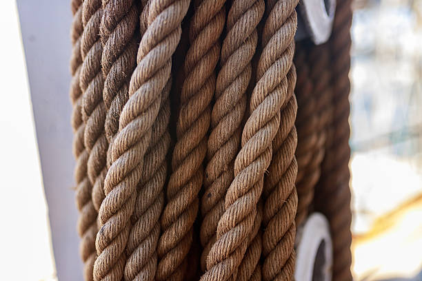 istock Detailed shot of twisted brown ship ropes coiled vertically with metal loop ends. 2220407172