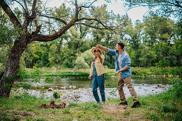 istock Couple enjoys a sunny day in nature while dancing by the river 2220410835