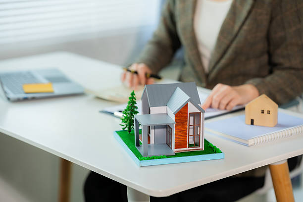 istock Asian real estate agent in modern office consulting with client, showing property using laptop, mortgage business with house plans, calculator and documents, mortgage and real estate 2220415048
