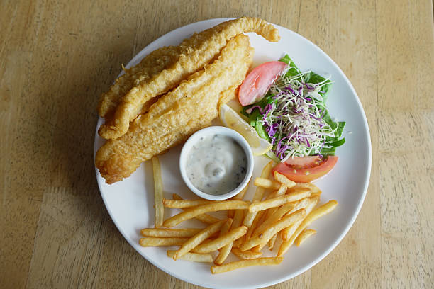 Enjoy a plate of crispy fried fish with fries and a fresh side salad.