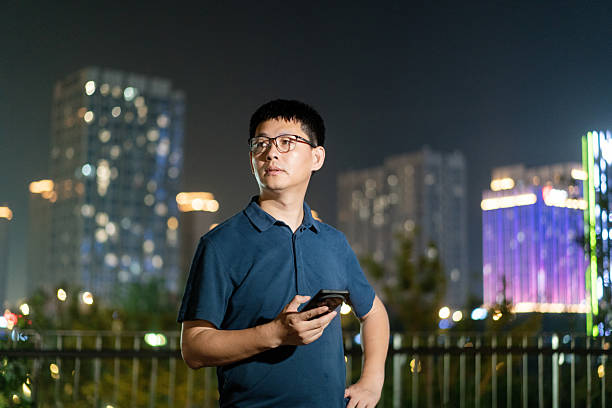 asian man using smart phone at night in city