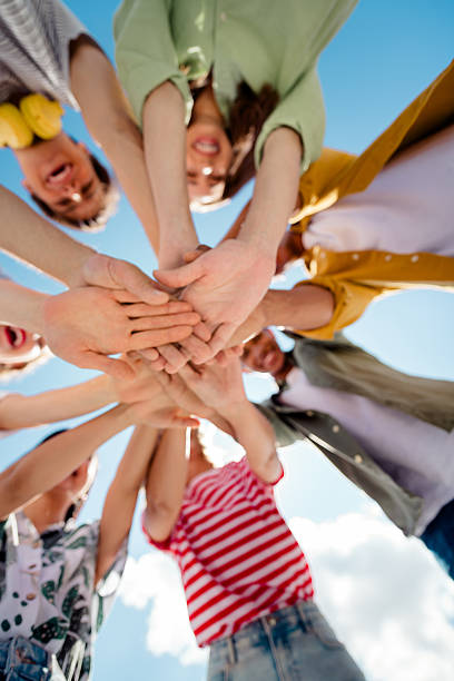 istock Diverse group of young best friends bonding and stacking hands outdoors on a sunny day, celebrating friendship and togetherness 2220424606