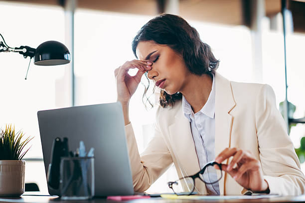 istock Professional businesswoman in modern office, looking concerned while holding glasses, demonstrating stress and fatigue 2220425312