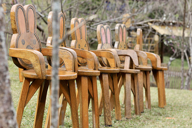 A Wooden chairs with rabbit shaped backs in grassy outdoor setting
