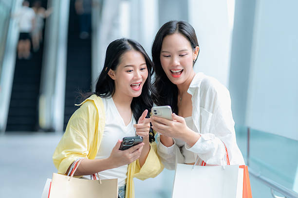 istock Excited Asian Women Looking at Smartphone While Shopping 2220428303