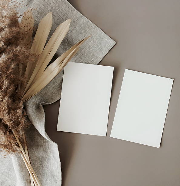 istock Blank cards mockup with copy space and dry palm leaf and grass top view on brown background . 2220430073