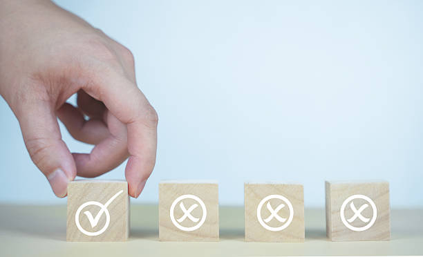 istock A hand selects a wooden cube with a check mark among others marked with X, symbolizing decision making, correct choice, recruitment, quality control, or evaluation. 2220430833