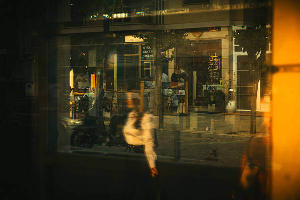 A layered, reflective urban scene captured through glass, blending movement, architecture, and human presence into a single moment. The photo offers a poetic representation of modern city life — fluid, fast, and fragmented — where people and their surroundings merge in reflections. Perfect for editorial content, conceptual storytelling, urban research, or visual communication about identity, modernity, and city dynamics in an ever-moving world.