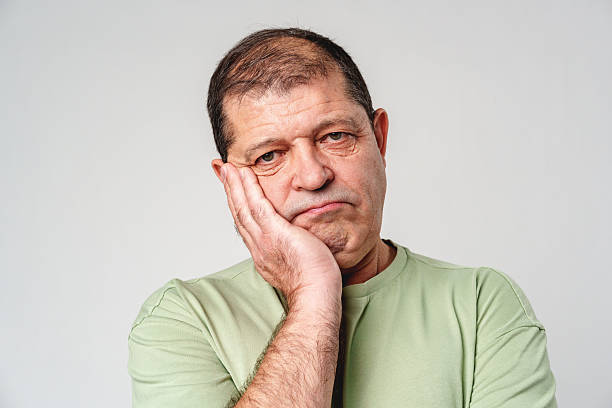 istock A middle-aged man shows a contemplative expression while resting his chin in his hand against a neutral background 2220432645