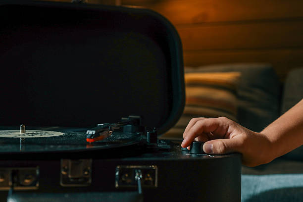 istock Close-up of hand adjusting volume knob on turntable while vinyl record plays, creating warm nostalgic atmosphere indoors 2220432745