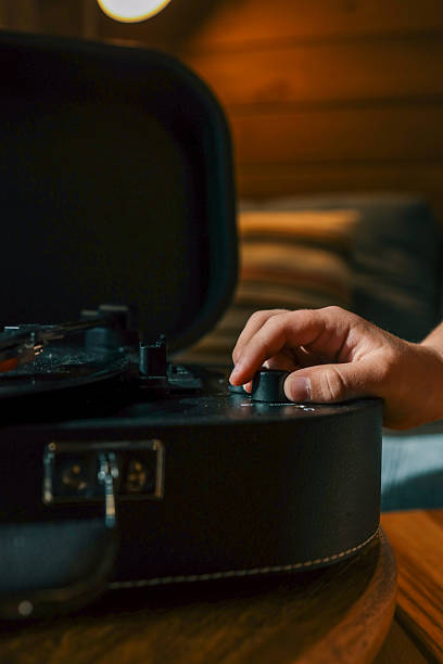 istock Close-up of hand adjusting volume knob on turntable while vinyl record plays, creating warm nostalgic atmosphere indoors 2220432757