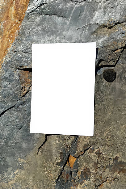 istock Mockup of white A4 sheet with shadows on large mountain stones in diffused sunlight. Layout of poster on stone background. White blank with space for text or design 2220433972