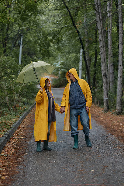 istock Happy embraced senior couple walking with umbrella at forest 2220436830