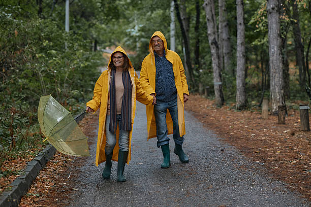 istock Happy embraced senior couple walking with umbrella at forest 2220436952