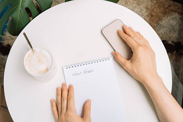 Digital detox moment person reaching for phone while resting with coffee and handwritten note slow down.