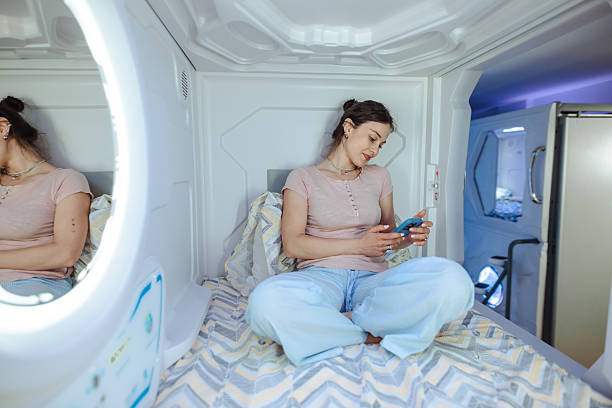 istock Young woman using smartphone inside modern capsule hotel room 2220442883