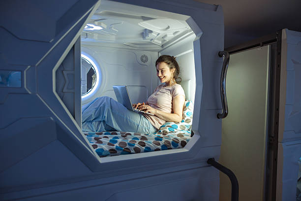 istock Woman using laptop comfortably in a modern sleeping capsule pod 2220442974