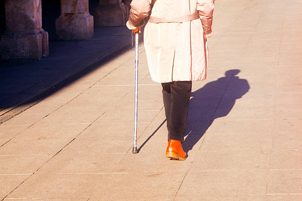 One woman walking on pedestrian zone with walking cane. Sunny weather in wintertime, Alcalá de Henares, Madrid,  Spain.