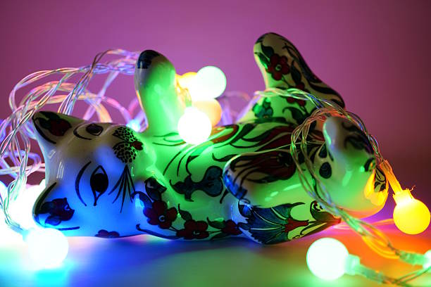 A ceramic toy cat and a glowing Christmas tree garland.
