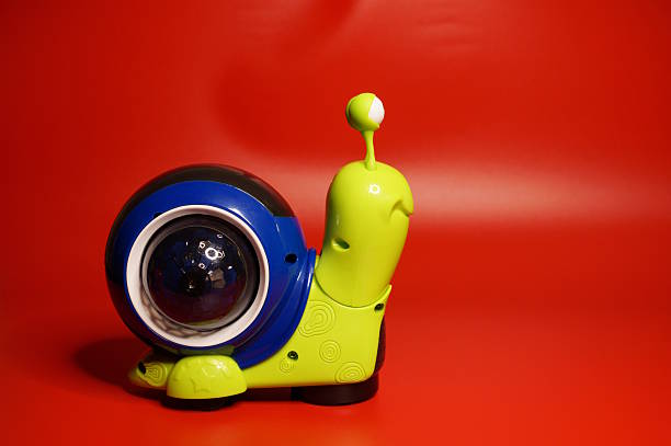 A toy snail on wheels. Red background.