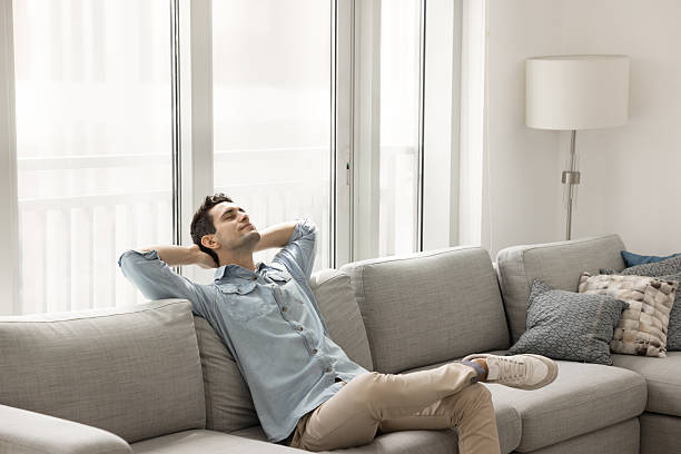 istock Carefree young guy lying back on sofa with eyes closed 2220447190