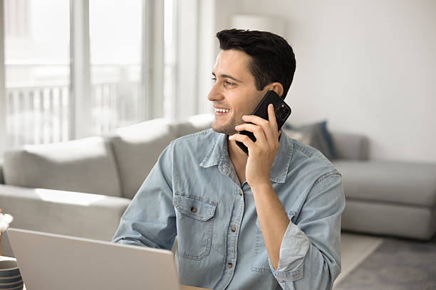 istock Young male entrepreneur speak by phone distracted from notebook screen 2220447933