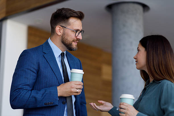 istock Two business partners are holding disposable coffee cups and talking during a coffee break at the office 2220449355
