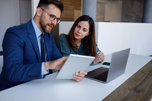 istock Two business professionals are working together, using a digital tablet and laptop in a bright, modern office environment 2220449793