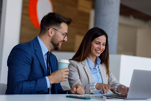 istock Two business people collaborating on a project, looking at laptop and smiling, enjoying their work 2220451441