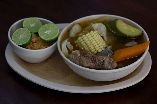 This hearty vegetable soup, served with corn and lime slices, highlights fresh produce, evoking warmth and home-cooked comfort in a visually appealing bowl.