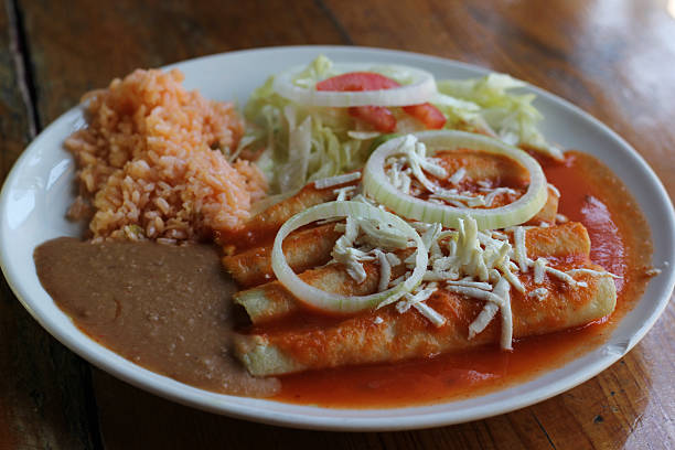istock A vibrant plate featuring cheese entomatadas topped with sauce, accompanied by rice, beans, shredded lettuce, onion, and tomato, highlighting traditional Mexican cuisine. 2220452711