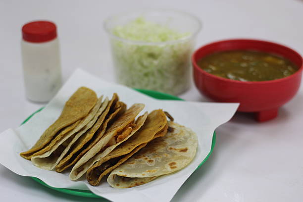 istock An enticing plate showcasing various tacos filled with flavorful mixtures, accompanied by fresh vegetables and a savory broth, perfect for sharing and enjoyment. 2220452732