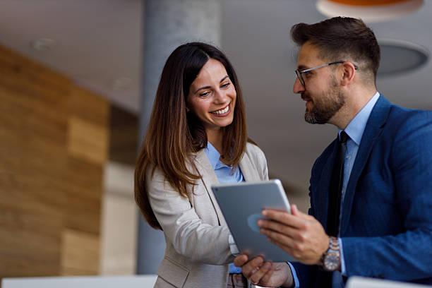 istock Two businesspeople are smiling and using a digital tablet in a modern office, discussing work and collaborating on a project 2220452760
