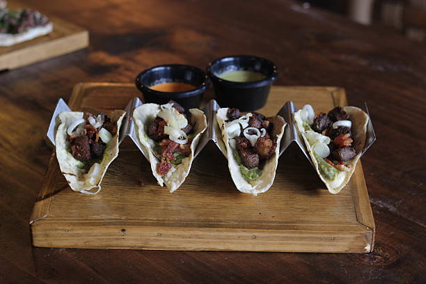 These exquisite tacos are beautifully arranged, filled with rich ingredients, and served with flavorful sauces on the side, perfect for sharing at a festive meal.