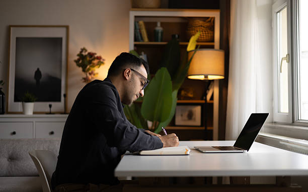 istock Young man writing in notebook at home 2220453931
