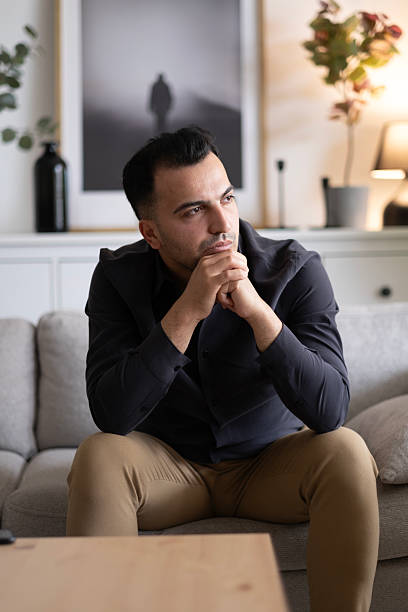 istock Man sitting alone at home looking sad and distraught 2220454075