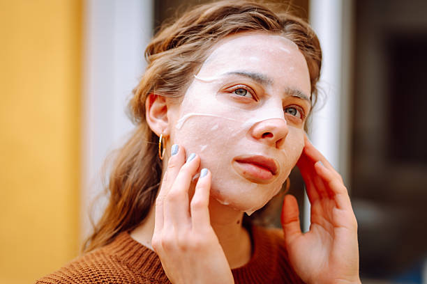 istock Woman in fabric face mask looking at her reflection in mirror enjoying time for herself. 2220454837