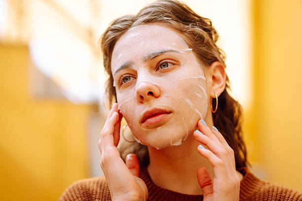 istock Woman in fabric face mask looking at her reflection in mirror enjoying time for herself. 2220454838