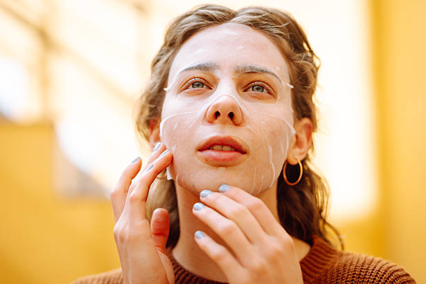 istock Woman in fabric face mask looking at her reflection in mirror enjoying time for herself. 2220454859
