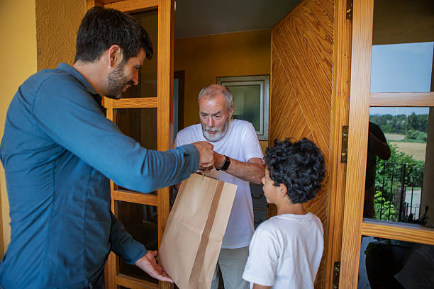 istock Father and son bring food to elderly man 2220456205