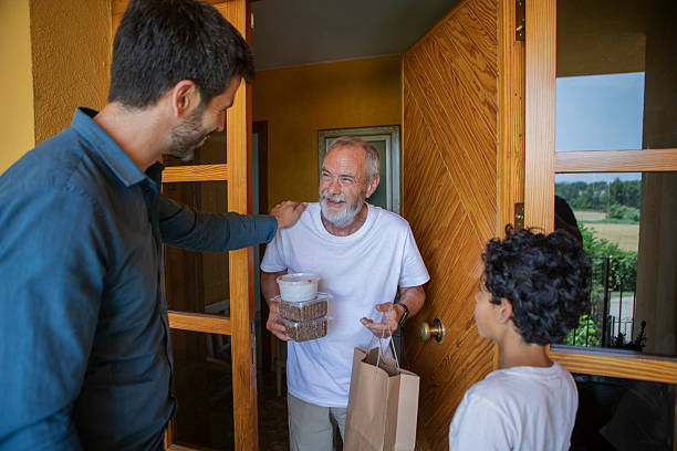 istock Father and son bring food to elderly man 2220456208