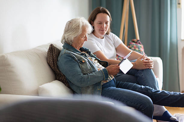 istock senior woman on sofa with adult daughter using digital tablet 2220457163
