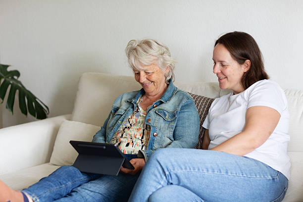 istock senior woman on sofa with adult daughter using digital tablet 2220457211