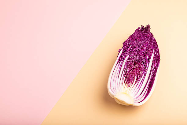 istock Purple Chinese cabbage on pink and orange pastel paper background, side view, copy space 2220458188