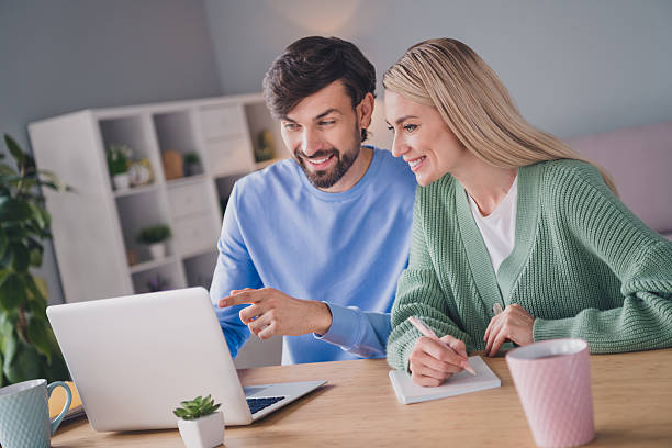 istock Portrait of two attractive cheerful people using laptop choosing order goods web service at home indoors 2220458762