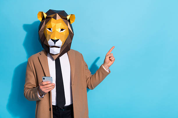 istock Photo of freak creative guy lion mask use device point finger empty space theme event notification isolated over blue color background 2220458812