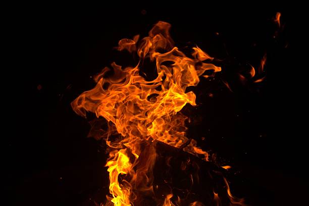 A dynamic close-up of bright orange flames against a dark background, capturing the energy and movement of fire.